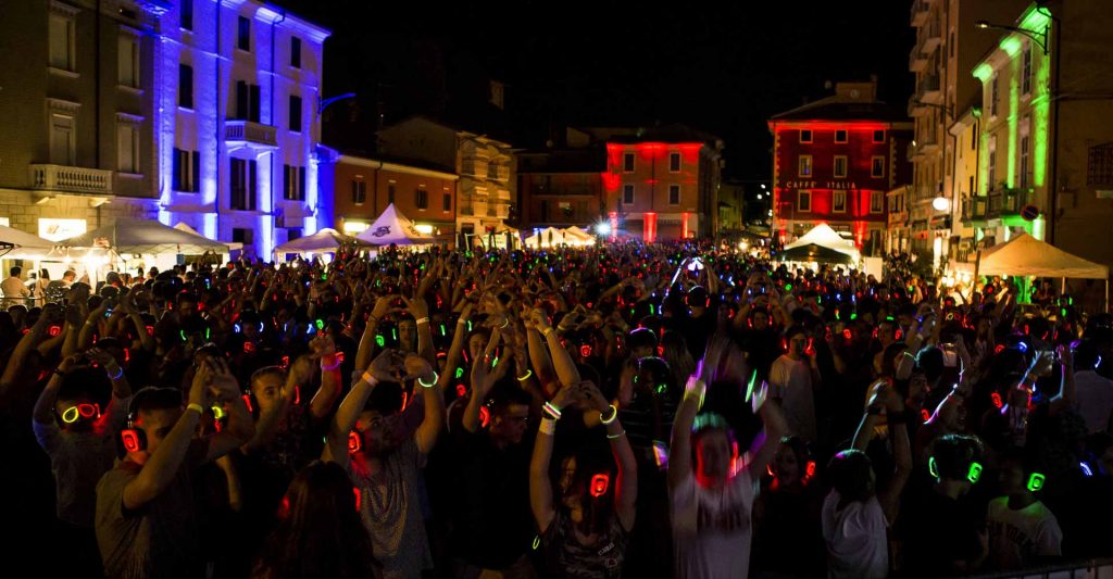 Torg på kvällen fullt av människor med silent disco-hörlurar
